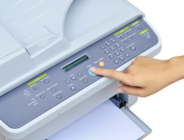 Kobieca dłoń wciskająca palcem przyciks na drukarce wielofunkcyjnej