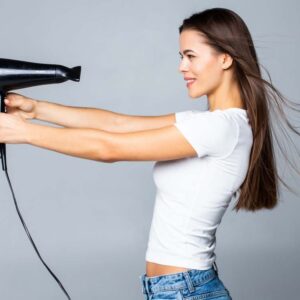 Test suszarek do włosów - ciemnowłosa kobieta trzyma suszarkę na wprost twarzy